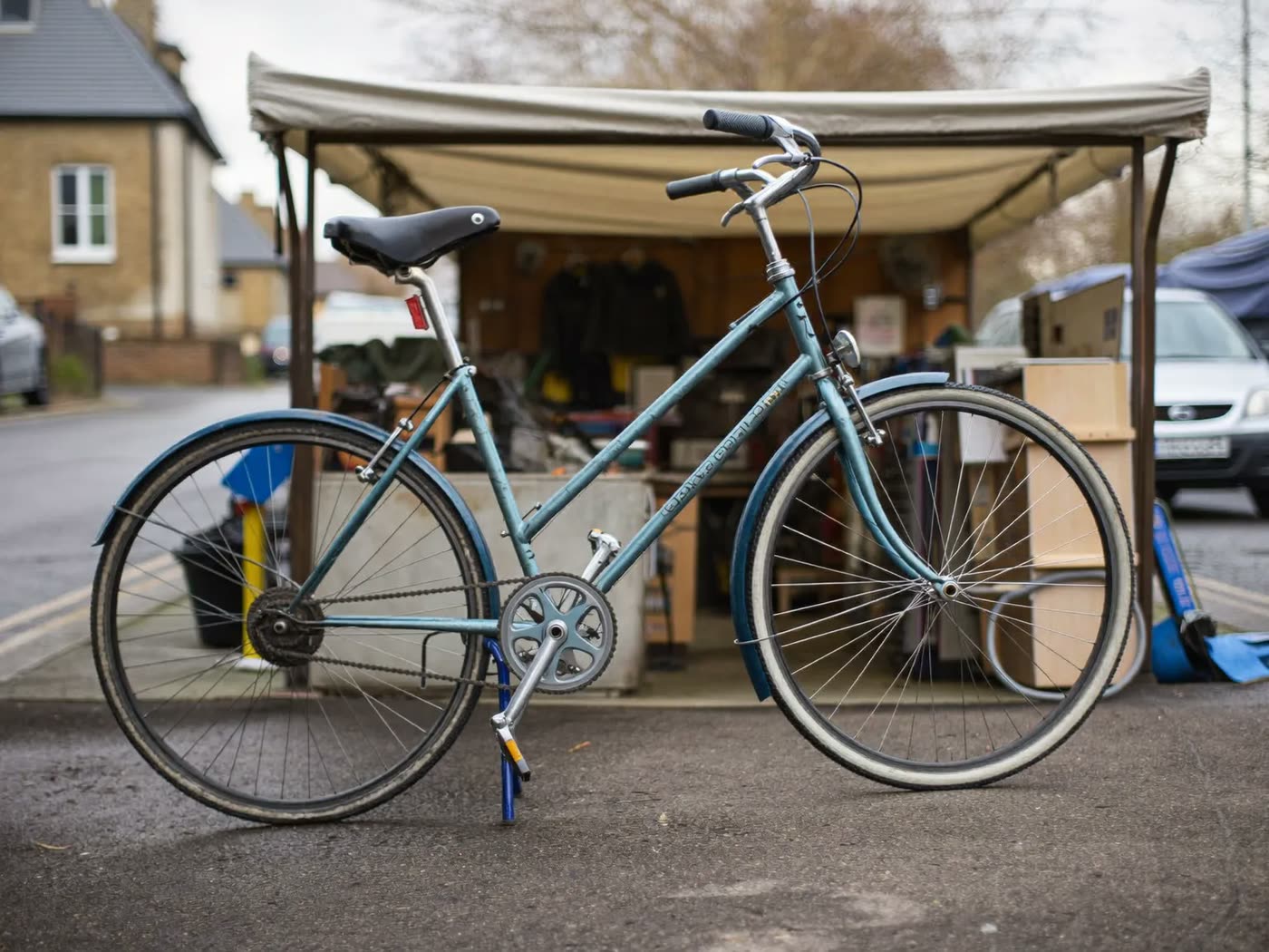 A repaired bicycle standing outside the workshop on a grey day